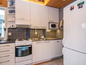 Een moderne keuken met witte kastjes, een ingebouwde oven, een magnetron en een vaatwasser.