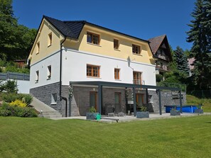 Ett tvåvåningshus med en balkong, en fasad av sten och en välskött gräsmatta.