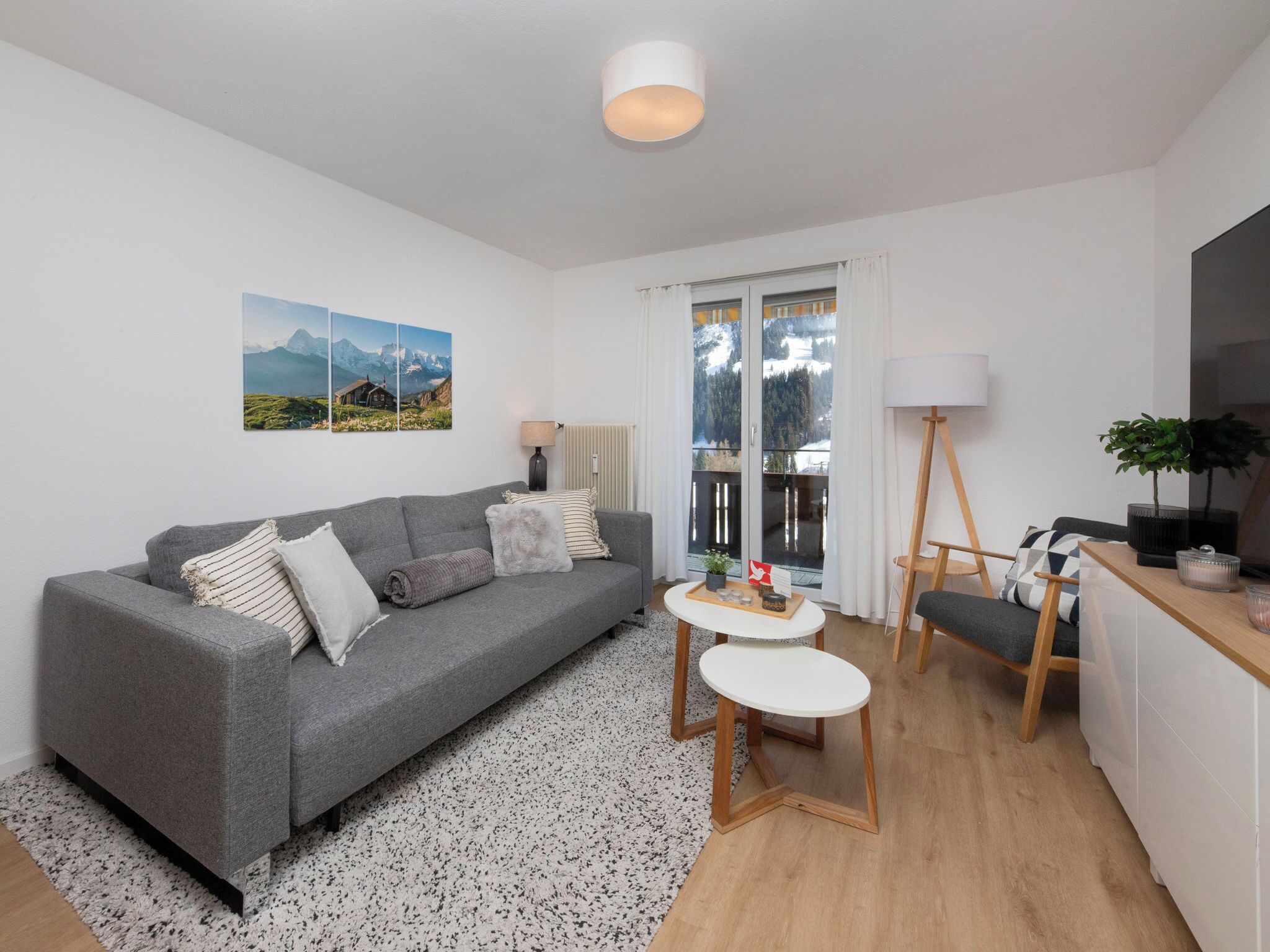 A modern living room with a grey sofa, a small round table, and a wooden chair.