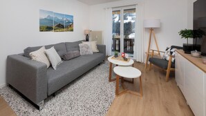 A modern living room with a grey sofa, a small round table, and a wooden chair. - Chalet zur Höhe by Interhome (Grindelwald)