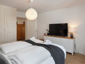 Una habitación de hotel moderna con cama, televisor, lámpara y armario.