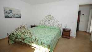 Un dormitorio con una cama, una mesita de noche, una lámpara de pared y un cuadro.