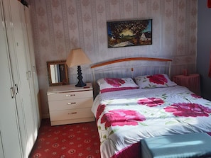 A bedroom with a bed, a nightstand, a dresser, a mirror, and a painting on the wall.