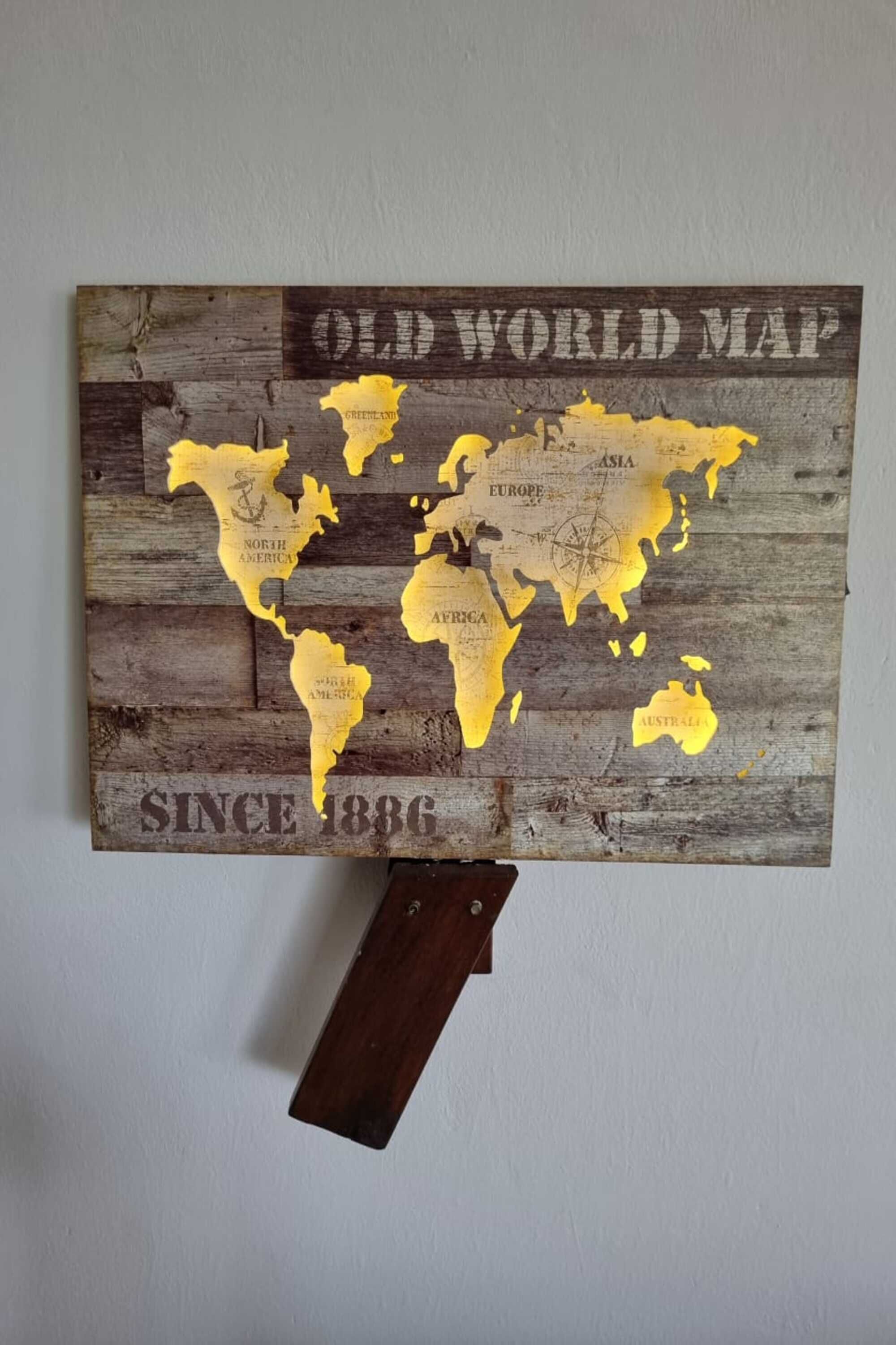 A wooden world map with 'OLD WORLD MAP' and 'SINCE 1886' text, mounted on a wall.