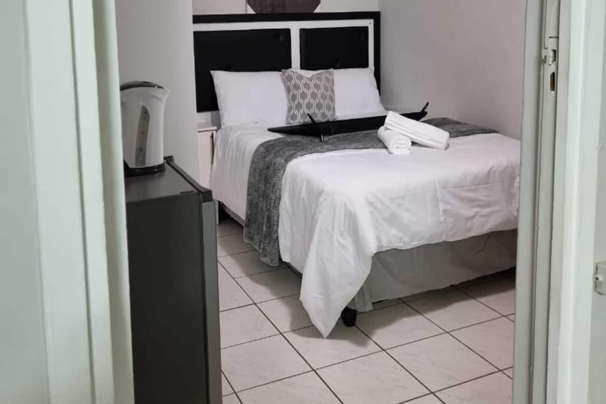 A bedroom with a bed, a ceiling fan, a wall-mounted artwork of a lion, and a tiled floor.