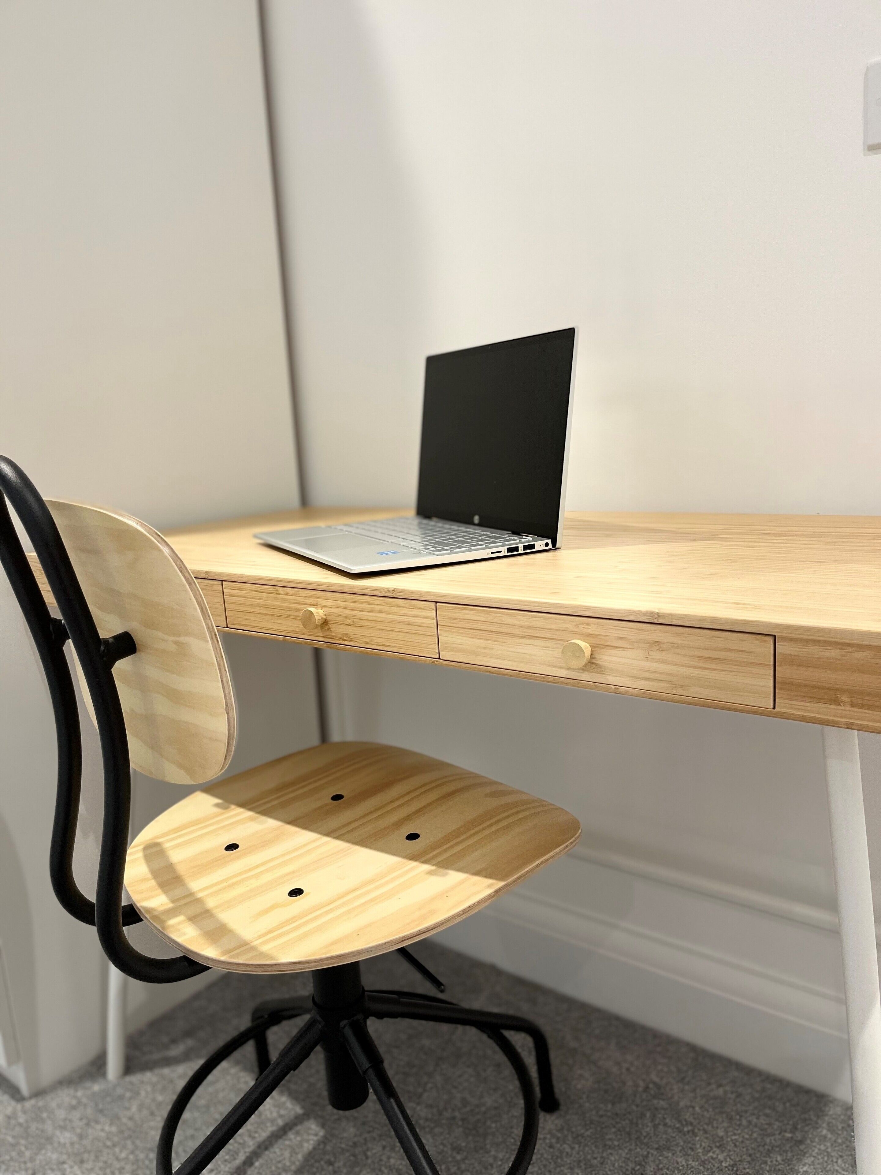 Un bureau en bois avec un ordinateur portable, une chaise et un tiroir.