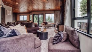 Un salon spacieux avec un plafond haut et de grandes fenêtres, aménagé avec des canapés et une table basse.
