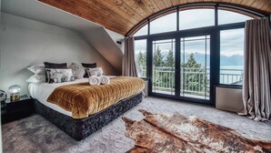 Une chambre avec un grand lit, une vue sur les montagnes et un plafond en bois.