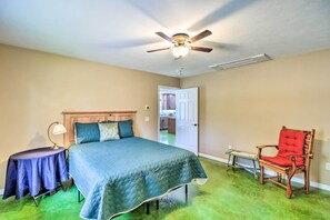 Une chambre à coucher avec un lit, une chaise, une table et un ventilateur de plafond.