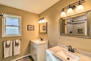 Une salle de bain avec une fenêtre, un lavabo, un miroir et un porte-serviettes.
