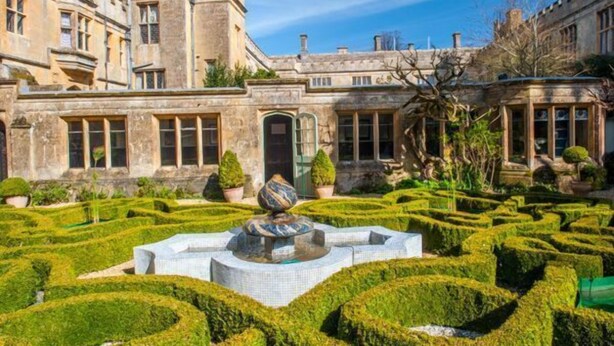 A historic building with a formal garden, including a fountain and geometrically trimmed hedges. - 2 bedroom Cotswold Holiday Home - Abbots Cottage (Winchcombe)