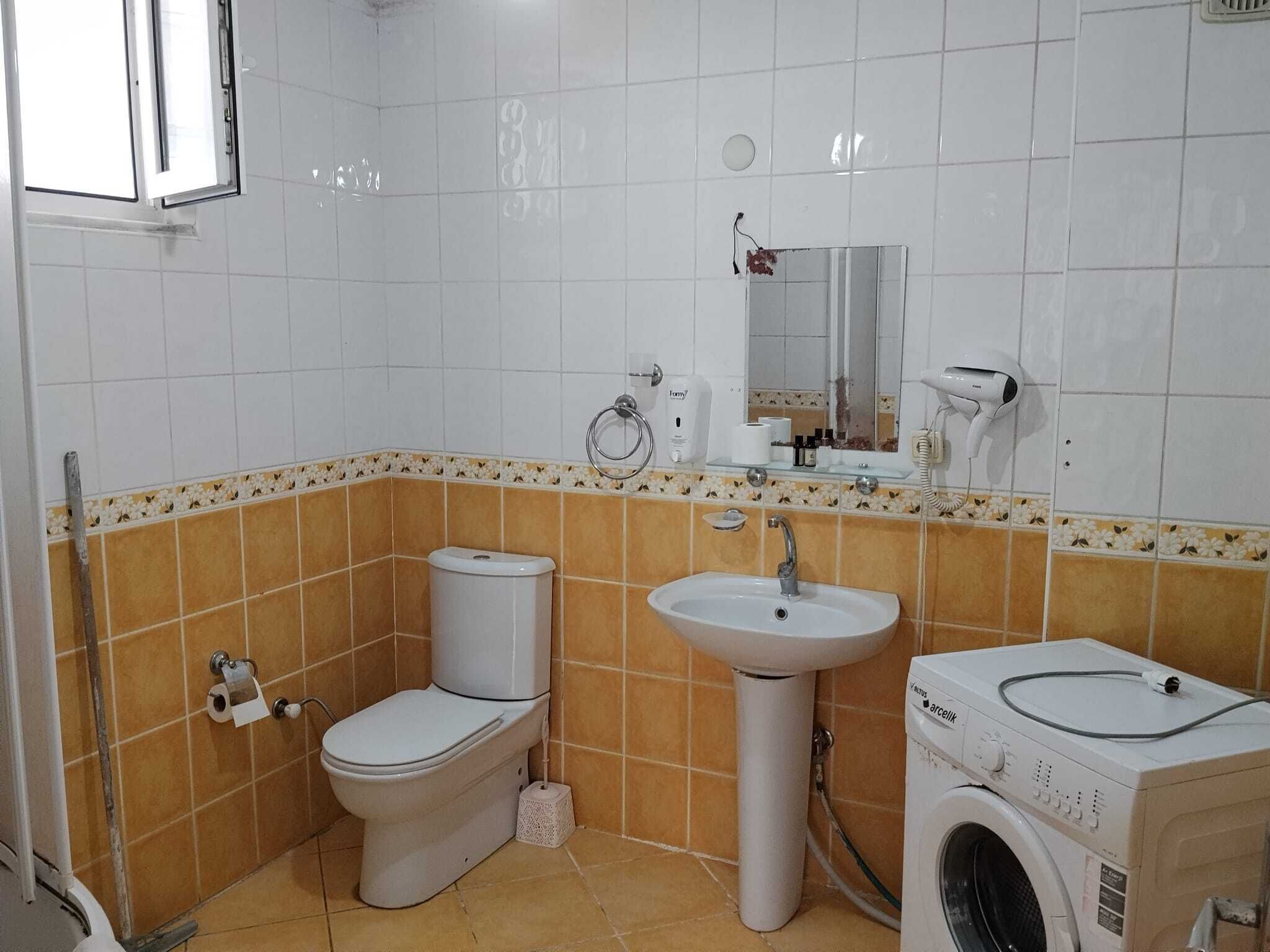 A bathroom with a toilet, sink, and washing machine.