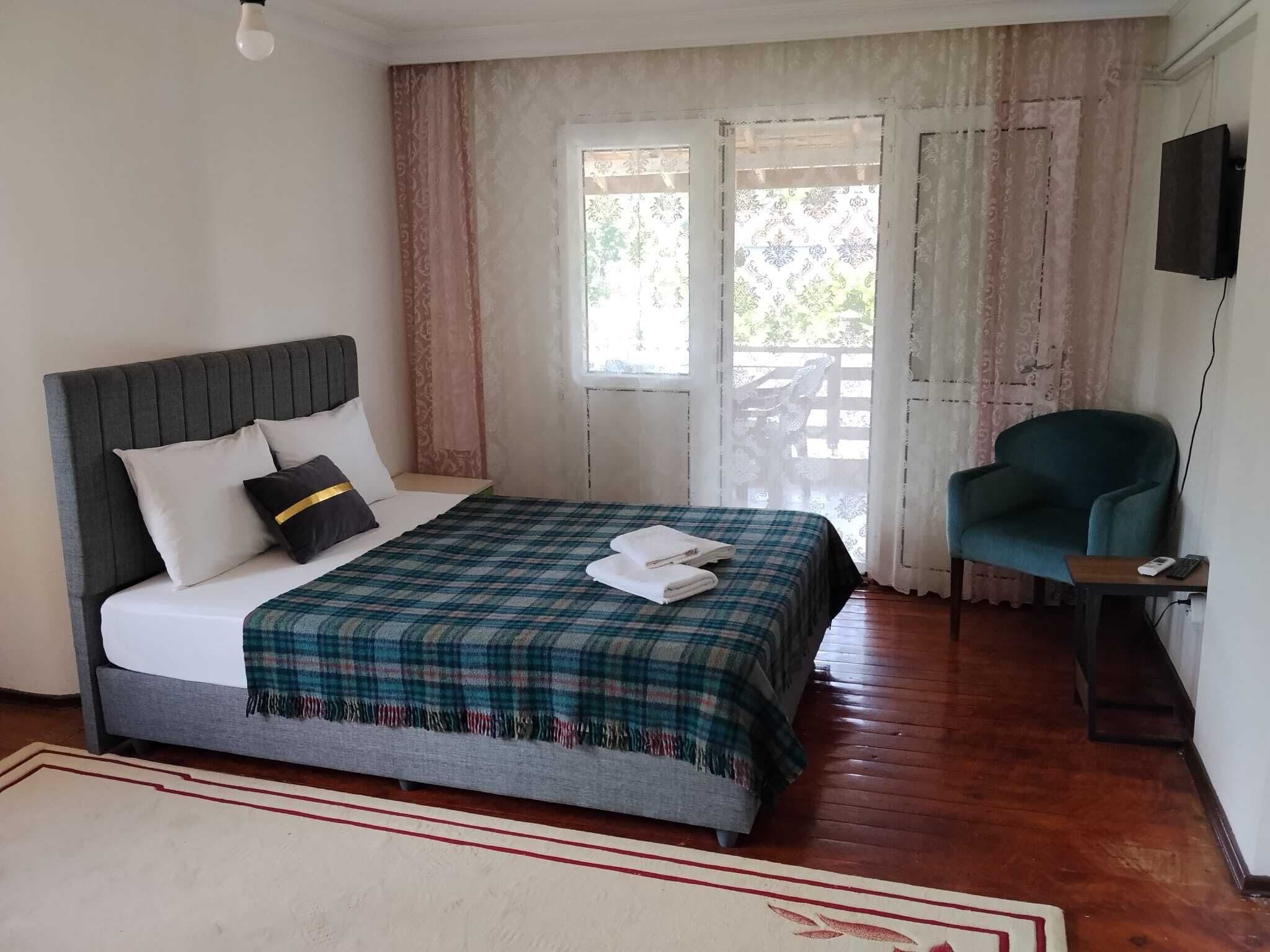 A bedroom with a bed, a chair, a desk, and a TV.