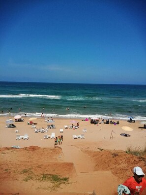 A beach with sun loungers, umbrellas, and people enjoying the water. - Melekler Pansiyon (Sile)