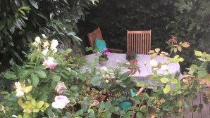 Un jardín con terraza de madera, una mesa y sillas.
