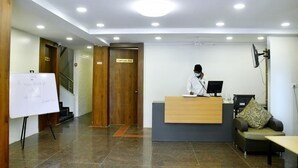 Un área de recepción con un mostrador para recepcionista, una pizarra y la puerta de una sala de conferencias.