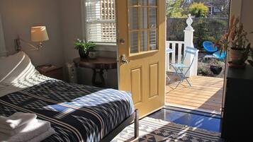 Quarto com cama, luminária de cabeceira e vista para o pátio externo.