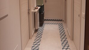 Un pasillo estrecho con suelo de diseño geométrico, paredes blancas y puertas a ambos lados.
