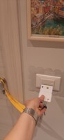 Una mano sosteniendo una llave cerca de la cerradura de una puerta y un interruptor de luz.