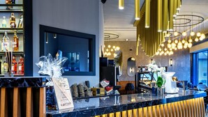 A modern reception area with a wooden reception desk, a digital screen, and a bar area with bottles. - Parkhotel Braunau  (Braunau am Inn)