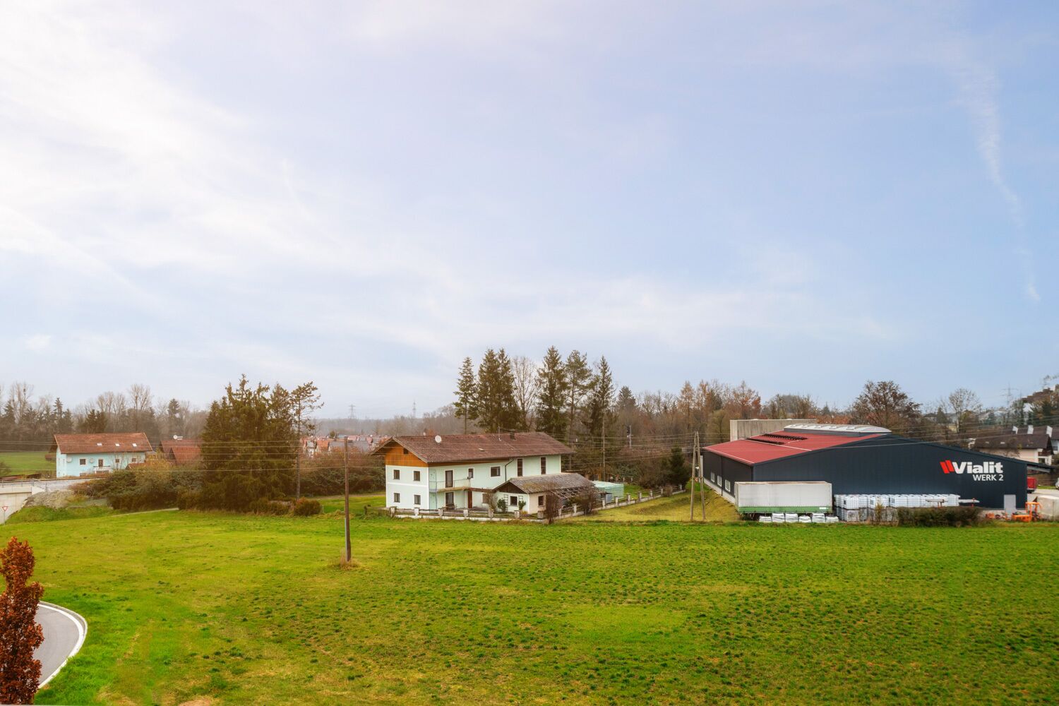 A rural landscape with a large industrial building labeled "Vialit Werk 2" and several residential houses.