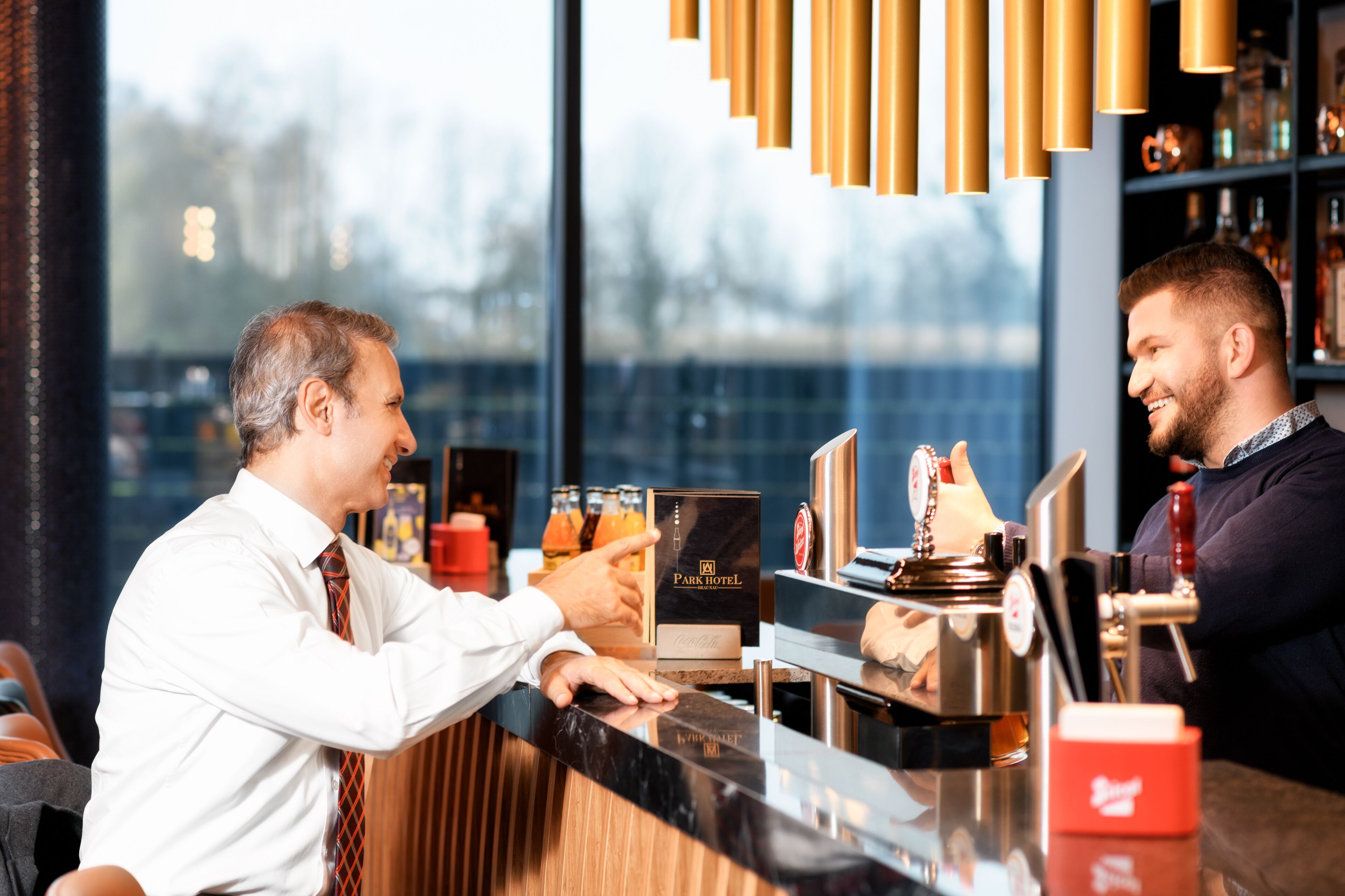 Eine Barbereich mit einer Theke, einer Kaffeemaschine und einem Regal mit Flaschen.