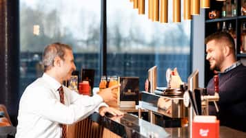 Eine Barbereich mit einer Theke, einer Kaffeemaschine und einem Regal mit Flaschen.