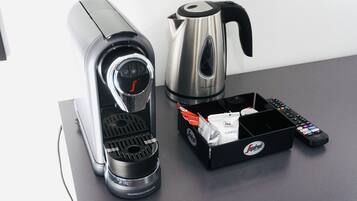A coffee maker, a kettle, and a remote control on a countertop.