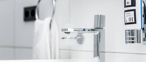 Un baño moderno con grifo de cromo, un perchero y un dispensador de jabón.