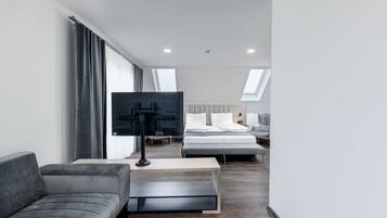 Een moderne hotelkamer met een bank, een televisie, een bed en een bureau.