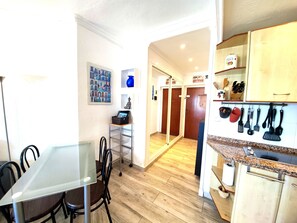 Une cuisine compacte avec des meubles en bois, un plan de travail en granit et un coin repas comprenant une table et des chaises en verre.