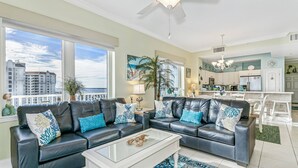 A living room with two black leather sofas, a glass coffee table, and a patterned rug. - Stay 5 Nights this Summer at Summerwinds West |15th Floor W/ Breathtaking Views |Beach Set Included (Navarre)