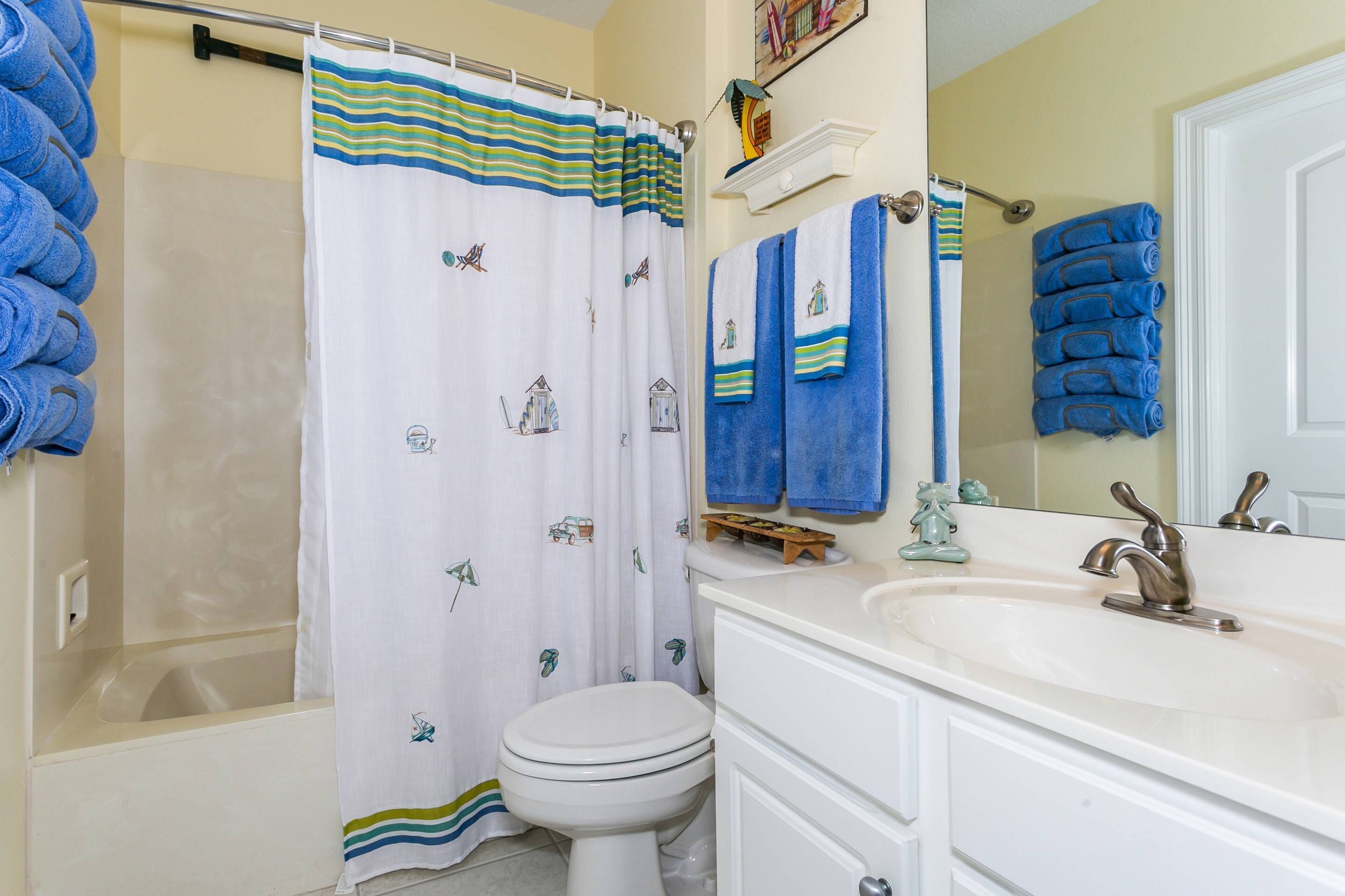 Un baño con bañera, inodoro y lavabo. Hay toallas y una cortina de ducha.