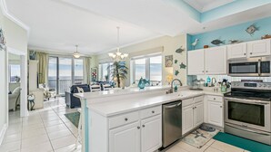 A spacious kitchen with white cabinetry, a central island, stainless steel appliances, and a view to the outside. - Stay 5 Nights this Summer at Summerwinds West |15th Floor W/ Breathtaking Views |Beach Set Included (Navarre)