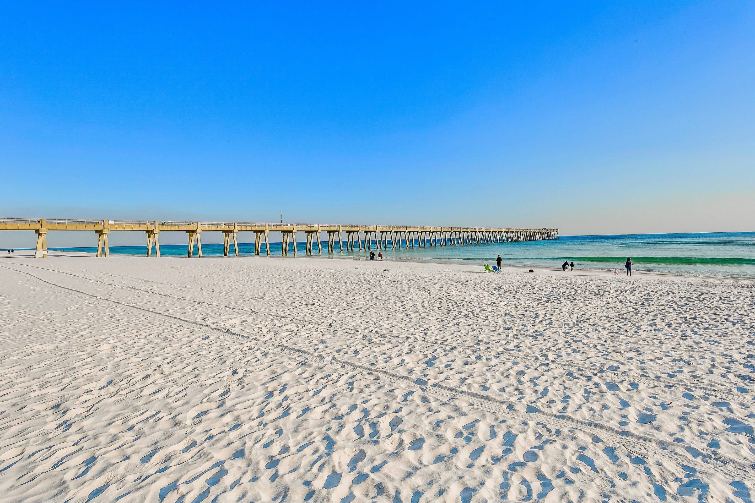 A beach with a pier extending into the ocean.