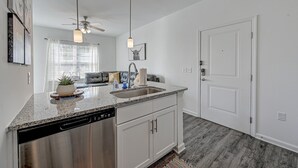 A kitchen with a dishwasher, a sink, and a ceiling fan. There is a window with blinds and a plant on the counter. - PrimRose Retreat in Orange Pk Nr. NAS JAX& ENTMT. (Jacksonville)