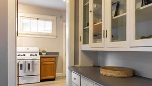 Een keuken met witte kasten, een fornuis en een houten aanrecht.