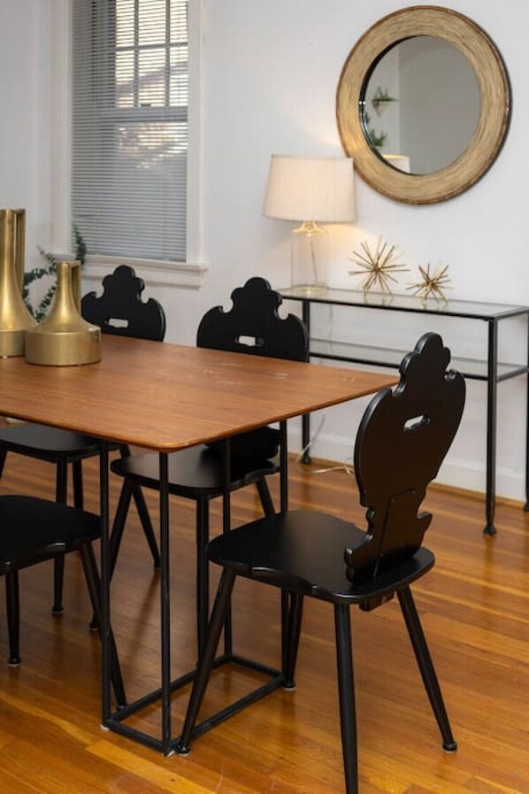 A dining area with a wooden table, black chairs, and a round mirror on the wall.