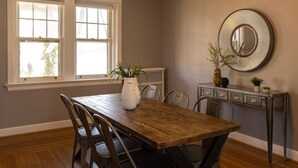 A dining area with a wooden table, chairs, a vase with plants, a mirror, and a dresser with drawers. - Spacious in Hyde Park with Patio (Cincinnati)