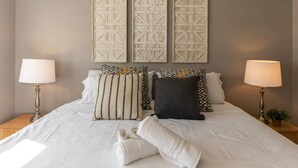 A neatly made bed with white linens, two bedside lamps, and patterned pillows. - Spacious in Hyde Park with Patio (Cincinnati)