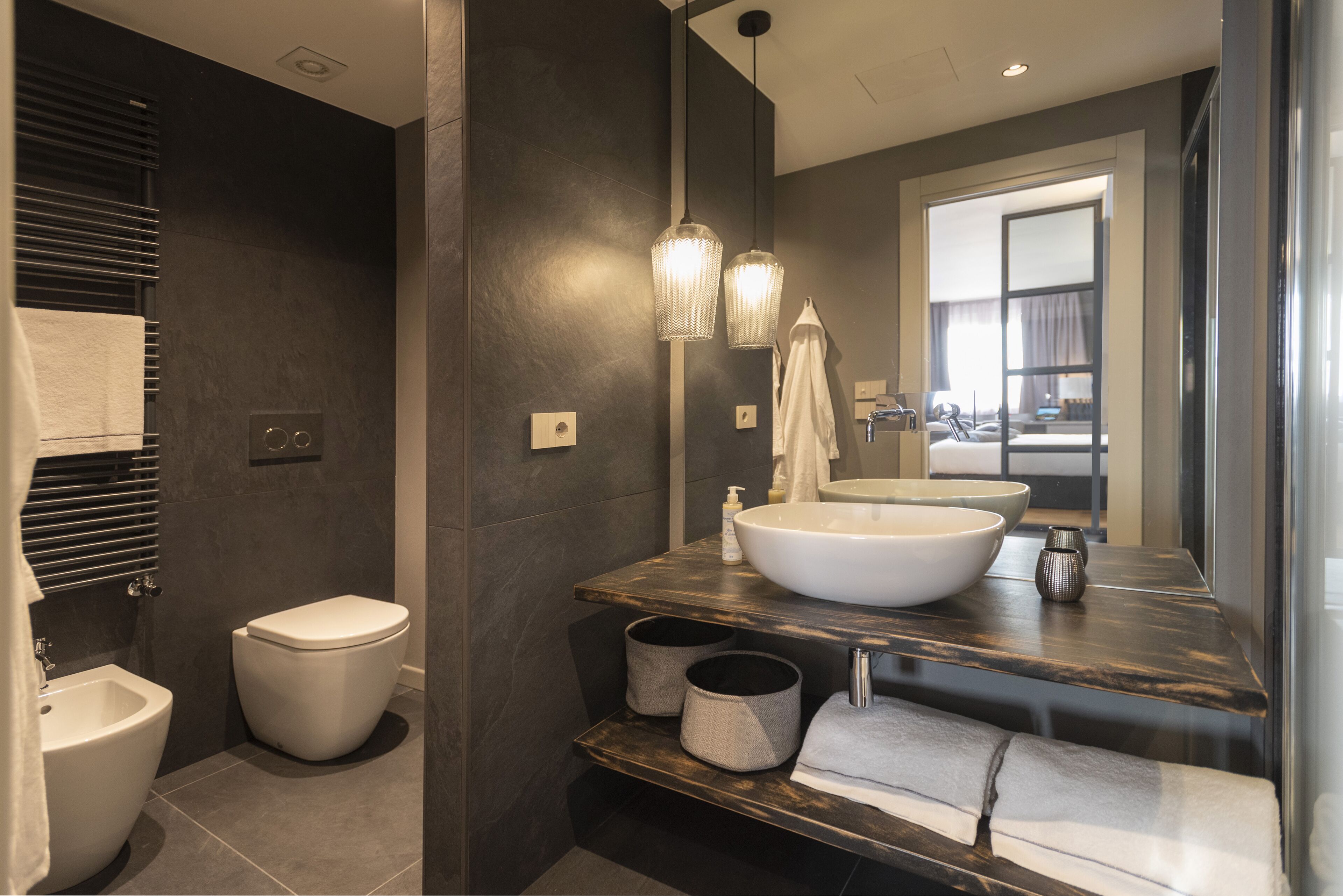 Une salle de bain moderne équipée d’un bidet, de toilettes, d’un grand lavabo et d’un miroir.