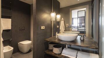 Une salle de bain moderne équipée d’un bidet, de toilettes, d’un grand lavabo et d’un miroir.