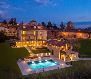 Uma casa grande e moderna com piscina e áreas de estar ao ar livre.