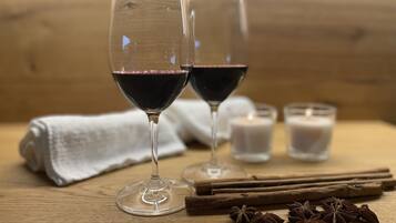 Dos copas de vino sobre una mesa de madera con mantel blanco, palitos de canela y anís estrellado.