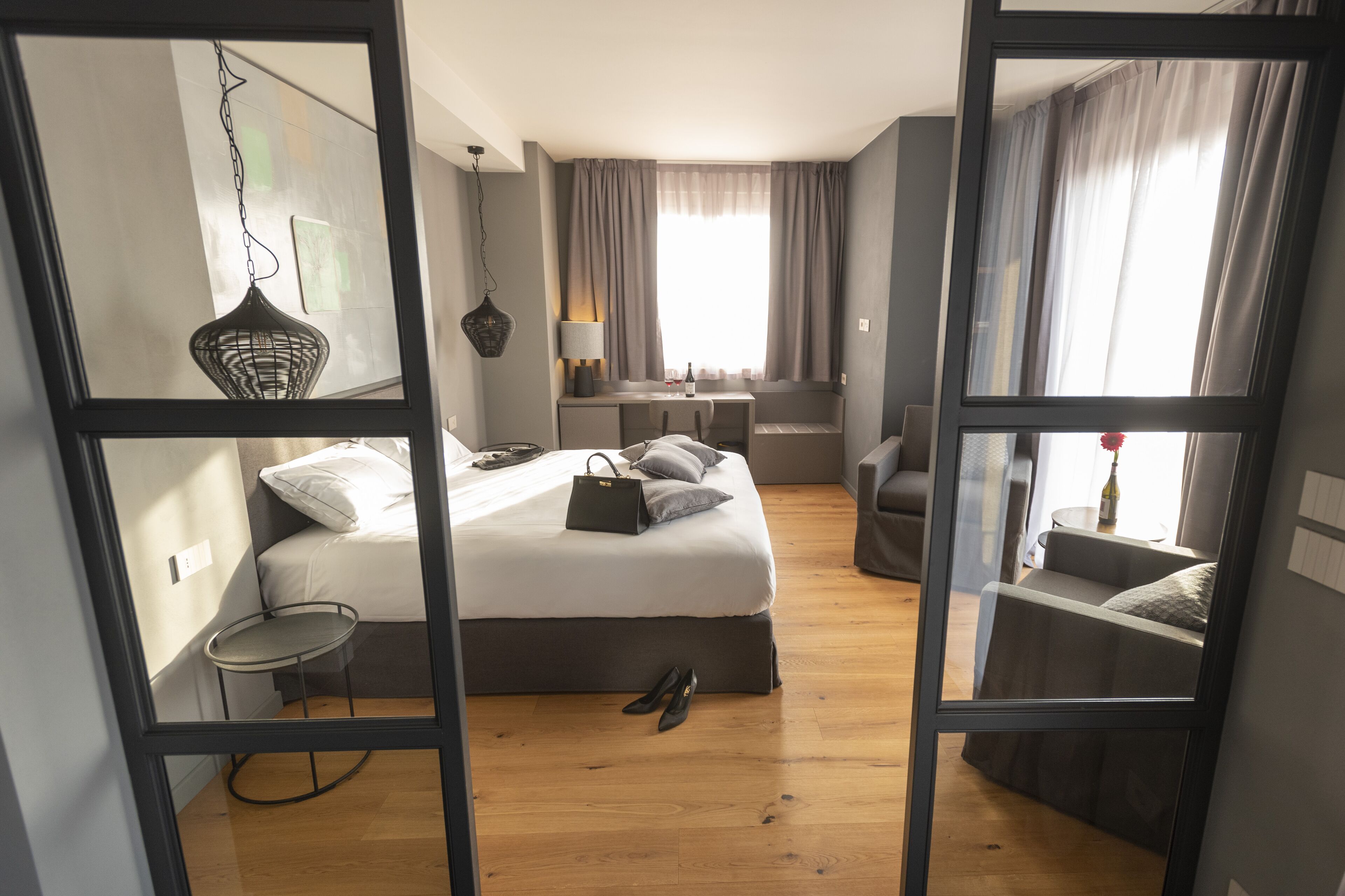 A modern bedroom with a bed, bedside table, lamp, and a view of the room through a mirror.