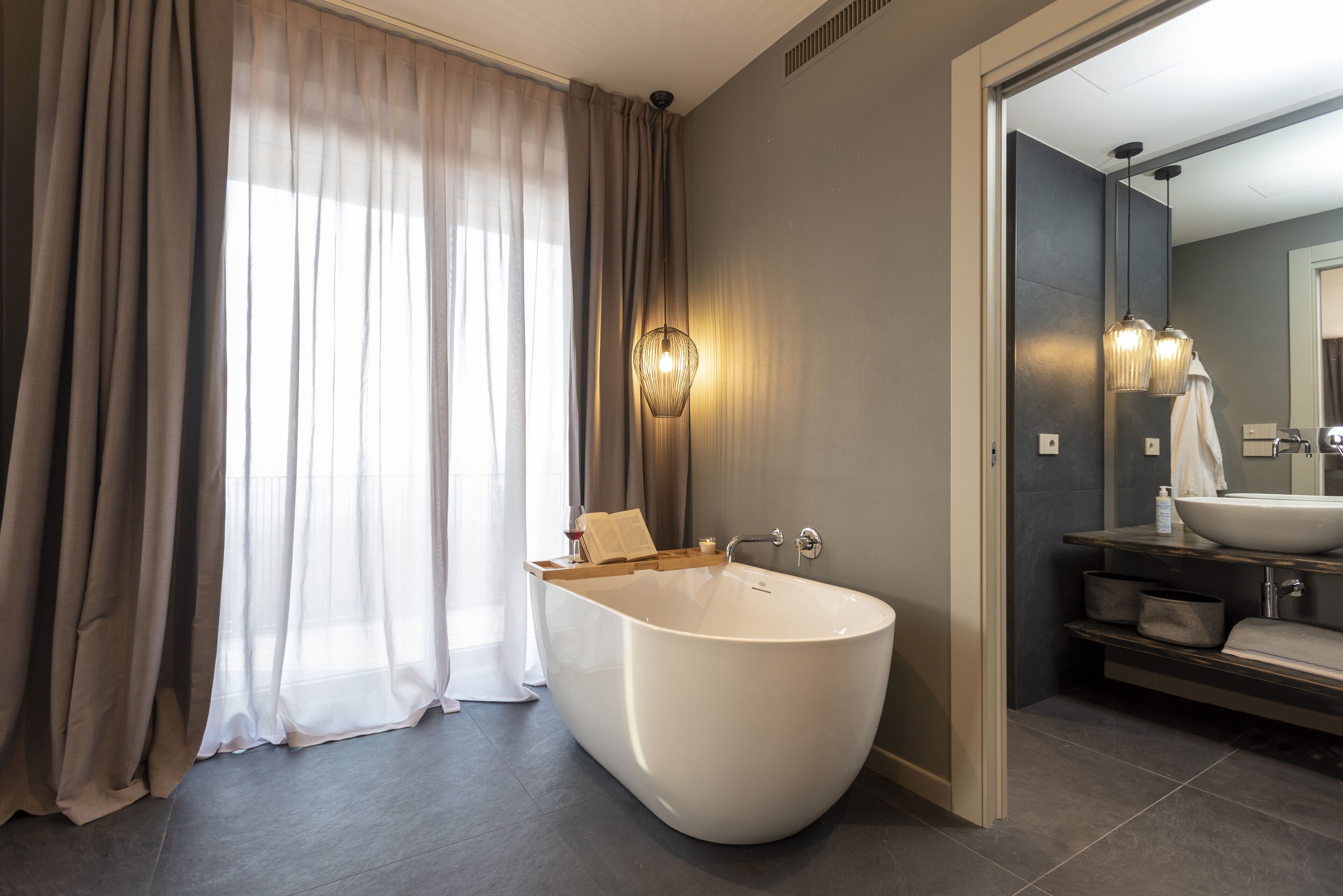 Un baño moderno con una bañera independiente, un tocador con un espejo grande y un perchero para toallas.