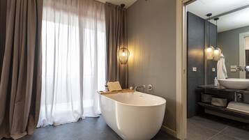 Un baño moderno con una bañera independiente, un tocador con un espejo grande y un perchero para toallas.