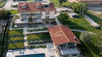 Ein zweistöckiges Haus mit Swimmingpool, umgeben von einem gepflegten Garten und Blick auf eine historische Stadt im Hintergrund.
