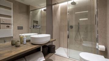 A modern bathroom with a large mirror, two sinks, a shower enclosure, and a toilet.