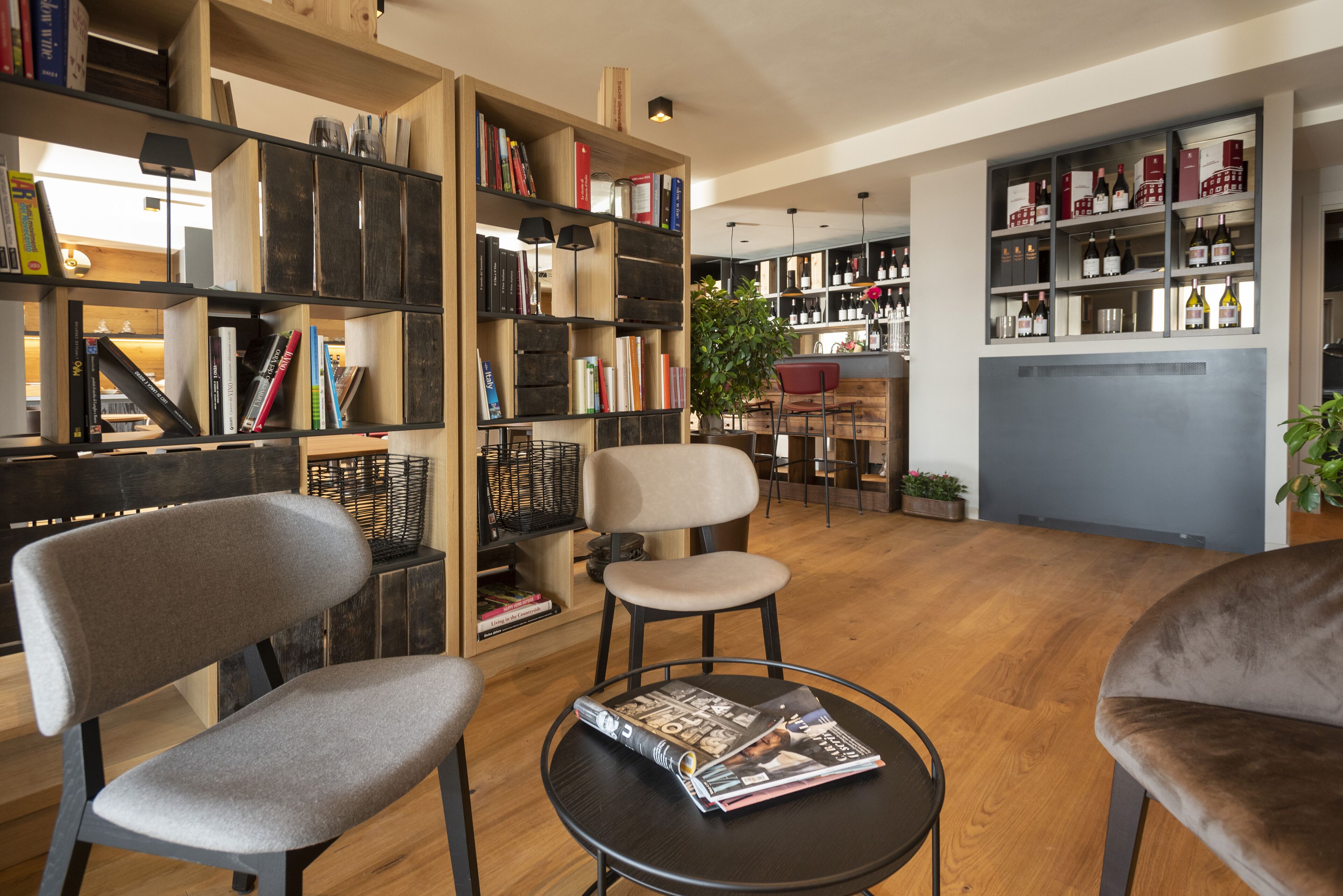 A modern interior with wooden bookshelves, a round table with magazines, and a seating area with chairs.